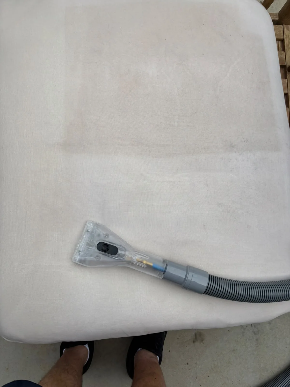 Upholstery cleaning nozzle working across a pale chair cushion