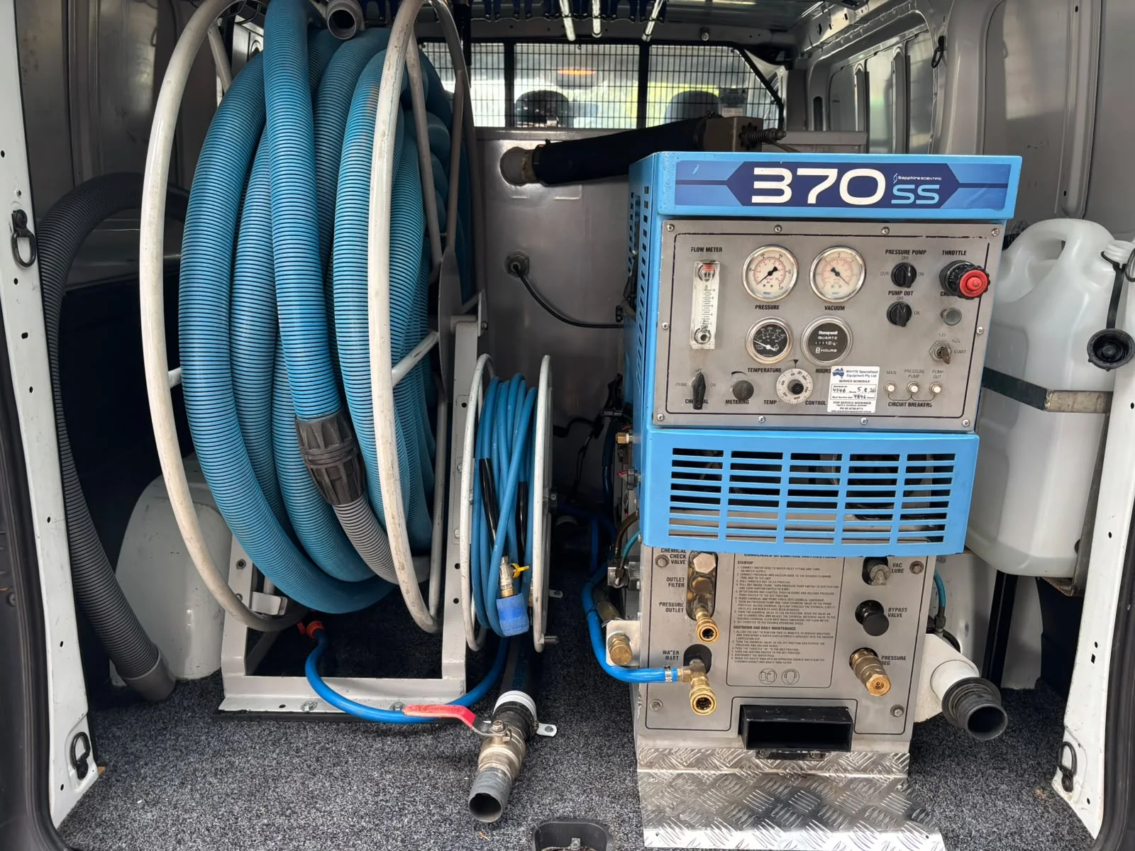 Truck-mounted carpet cleaning machine and coiled hoses fitted in the rear of a work van