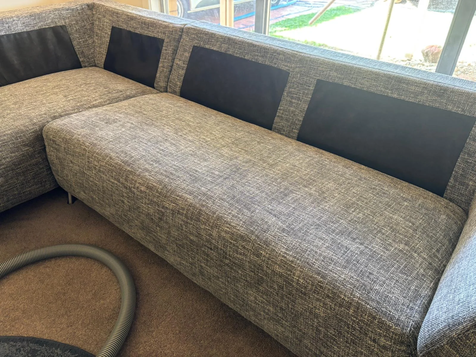 Grey upholstered sofa with one cushion visibly cleaned