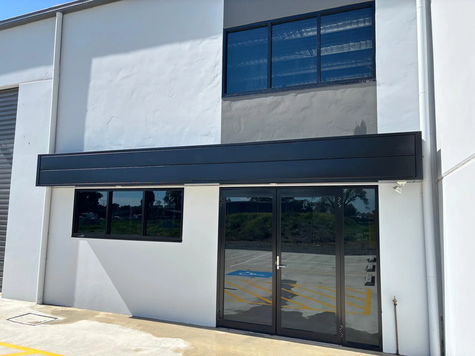 Clean dark-framed windows and glass doors on a white commercial building